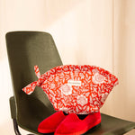Grande trousse froufrou Antioche Tomato posée sur une chaise verte, avec des ballerines