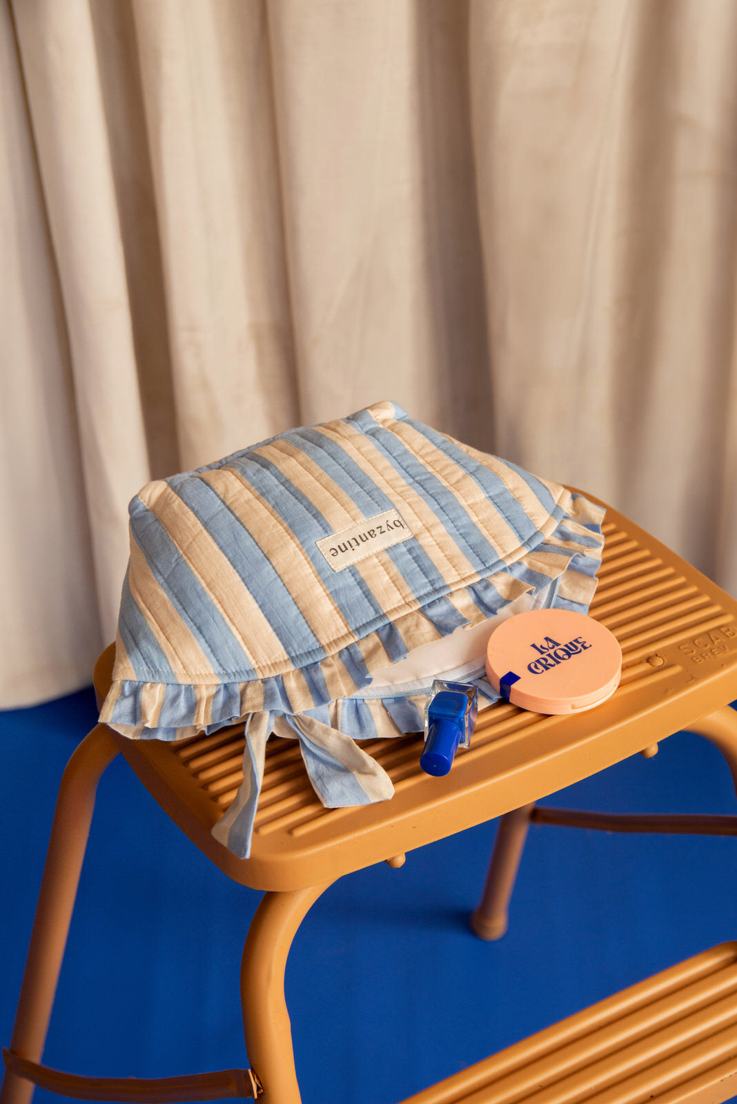 Grande trousse froufrou Pacha Bleu ciel posée sur un escabeau en bois, avec un miroir