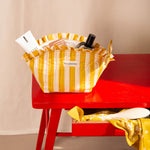 Grande trousse froufrou Pacha Passion ouverte sur une table rouge, remplie de soins