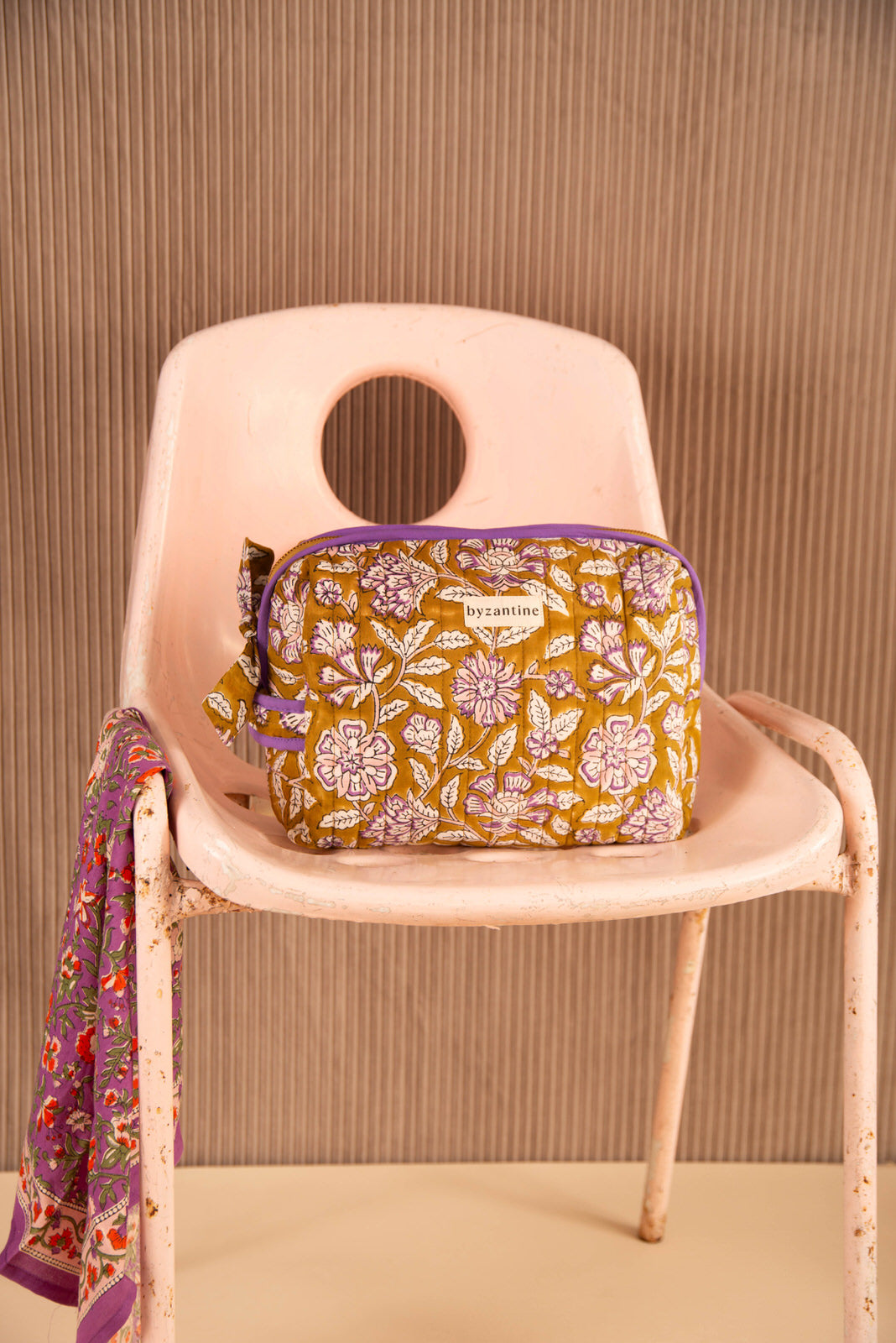 Grande trousse de toilette Carthage Kaki de Byzantine, passepoil violet, sur une chaise rose