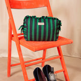 Grande trousse volants Pacha Menthe sur une chaise orange, mocassins en velours au sol