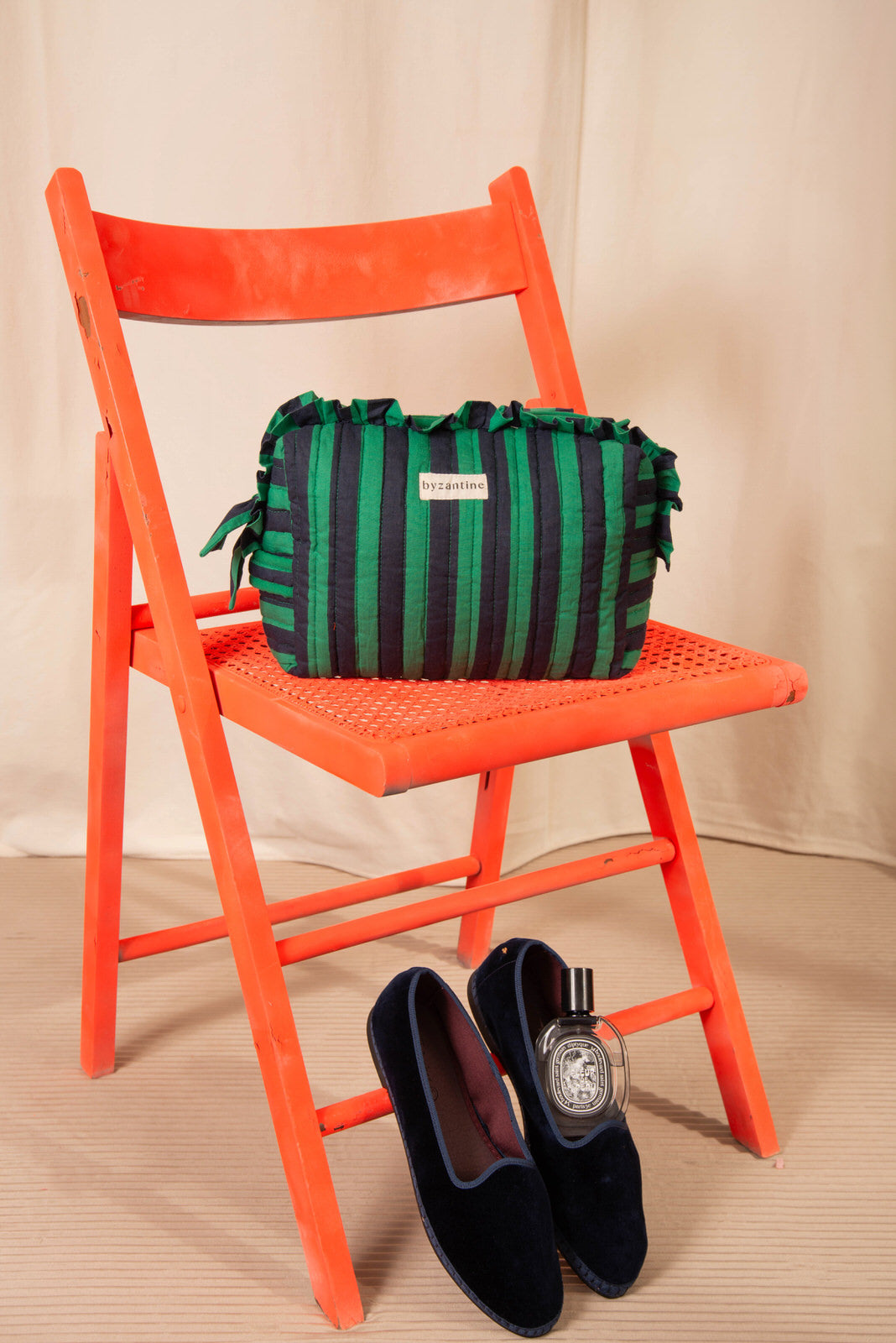 Grande trousse volants Pacha Menthe sur une chaise orange, mocassins en velours au sol