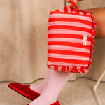 Grande trousse volants Pacha Tomato tenue à la main, ballerines rouges en velours