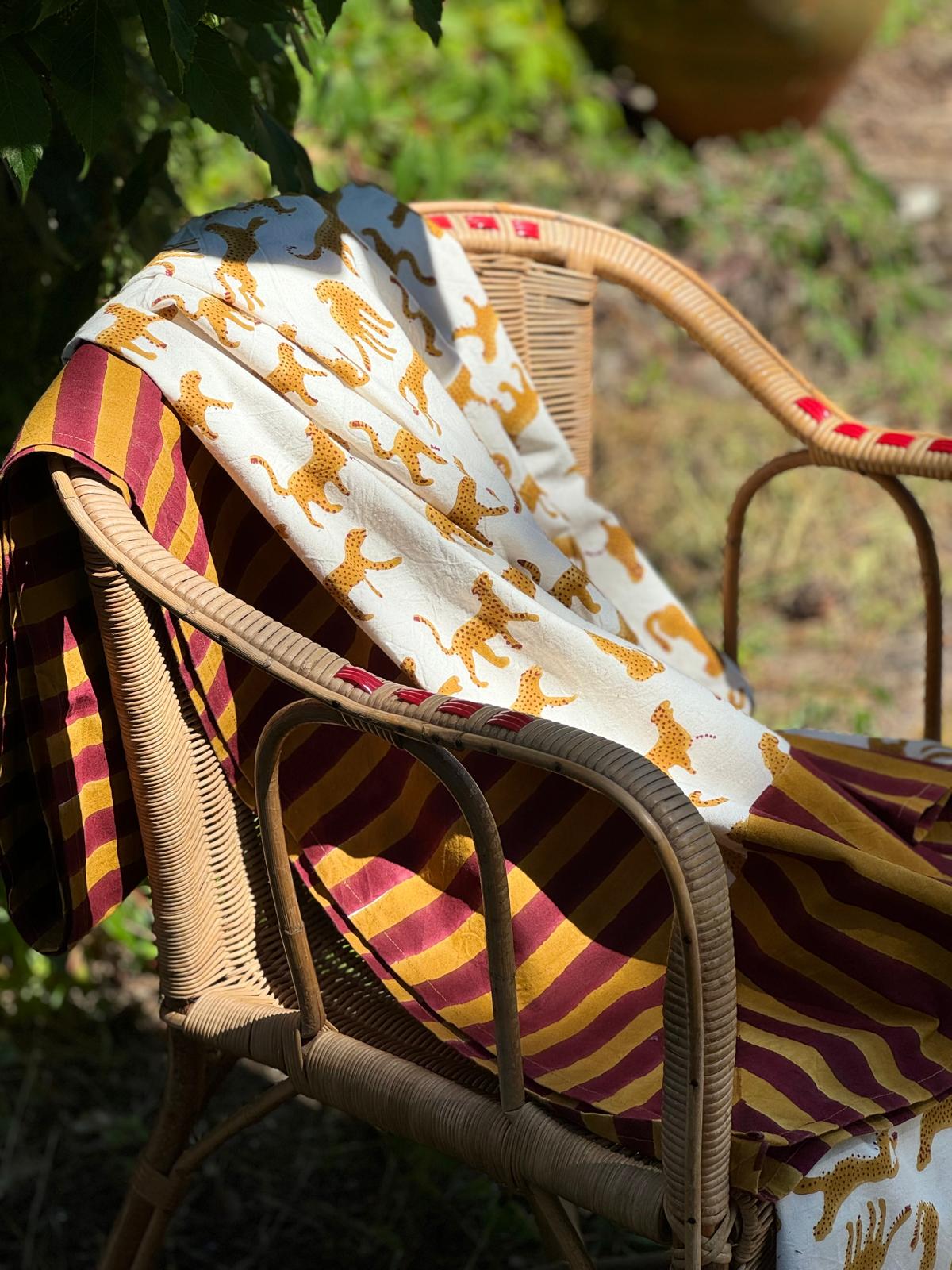 Nappe indienne Fauve Écru drapée sur un fauteuil en rotin dans un jardin