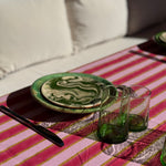 Nappe Byzantine rayée rose camélia dressée avec assiettes vertes et verres