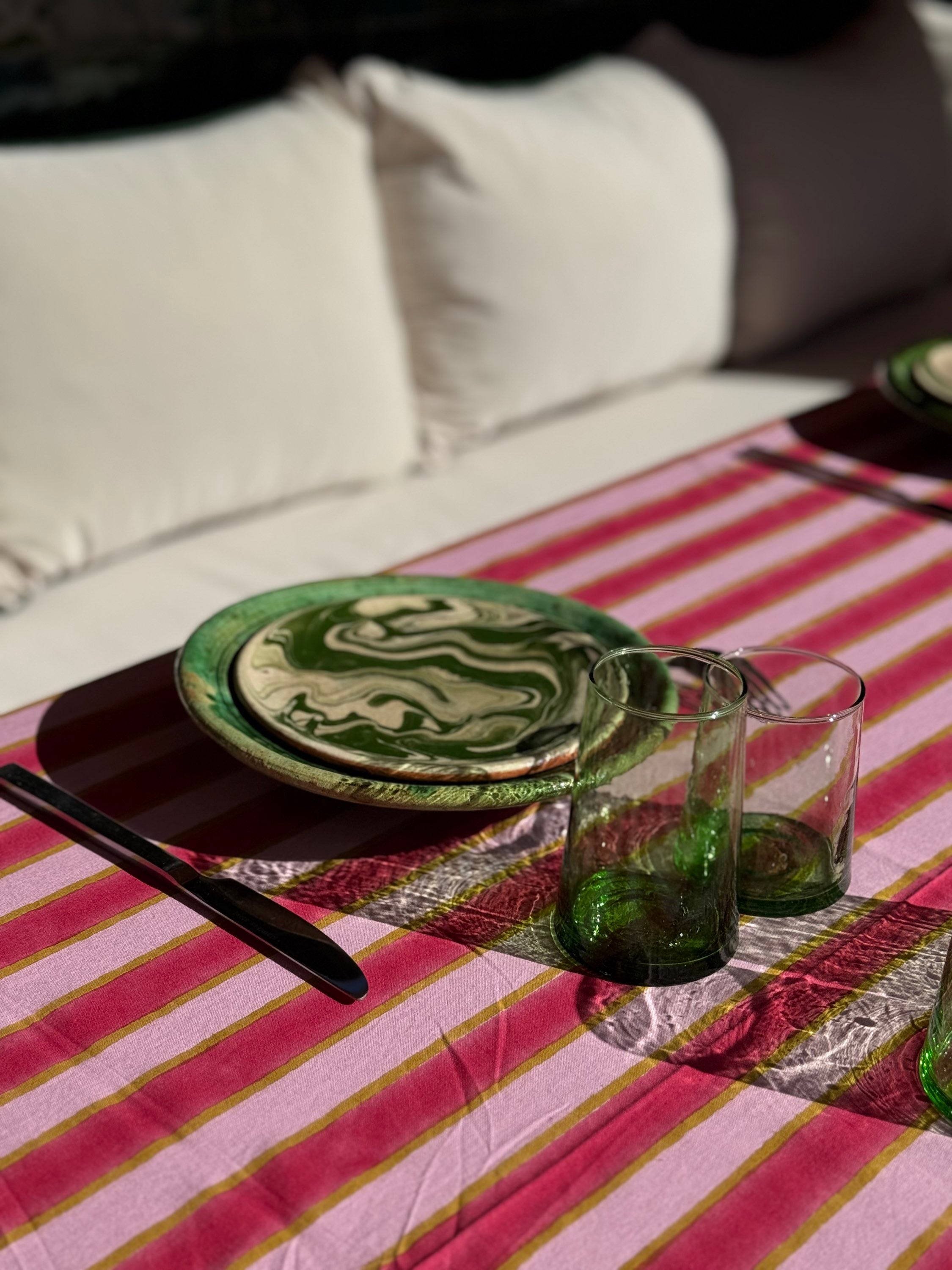 Nappe Byzantine rayée rose camélia dressée avec assiettes vertes et verres
