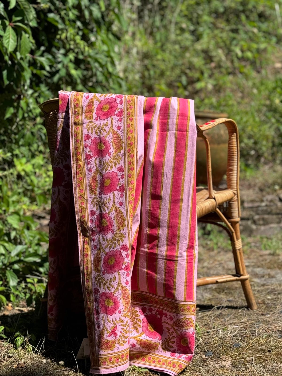 Nappe rayée Camélia Rose drapée sur une chaise dans un jardin