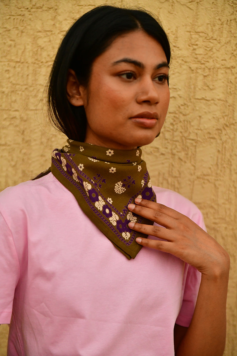 Petit foulard Anastase Olive porté au cou, main posée sur le foulard