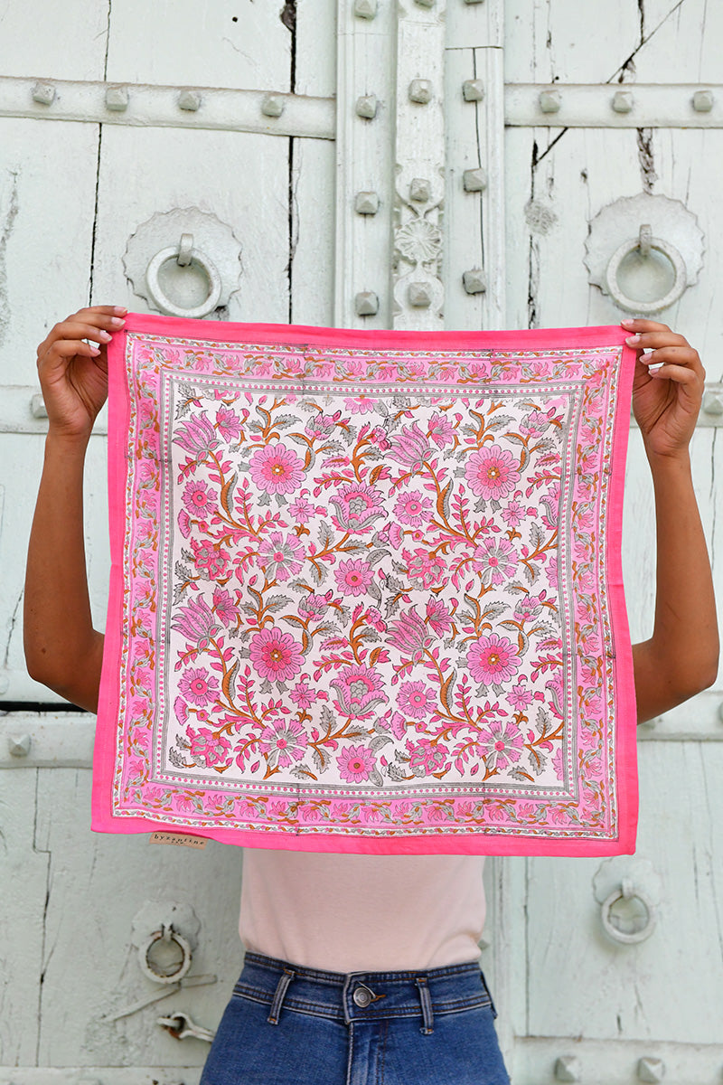 Petit foulard Andromaque Rose de byzantine déplié, tenu devant une porte blanche