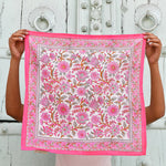 Petit foulard Andromaque Rose de byzantine déplié, tenu devant une porte blanche