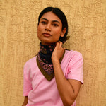 Petit foulard Antigone Nuit noué au cou, porté avec un tee-shirt rose