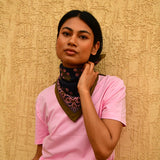 Petit foulard Antigone Nuit noué au cou, porté avec un tee-shirt rose