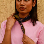 Petit foulard Antigone Nuit noué au cou, mains sur le foulard