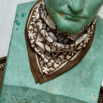petit foulard fleuri kaki et écru porté en point par une statue