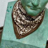 petit foulard fleuri kaki et écru porté en point par une statue