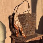 Petit foulard Antoinette Beige de byzantine noué à un panier en osier sur un tabouret