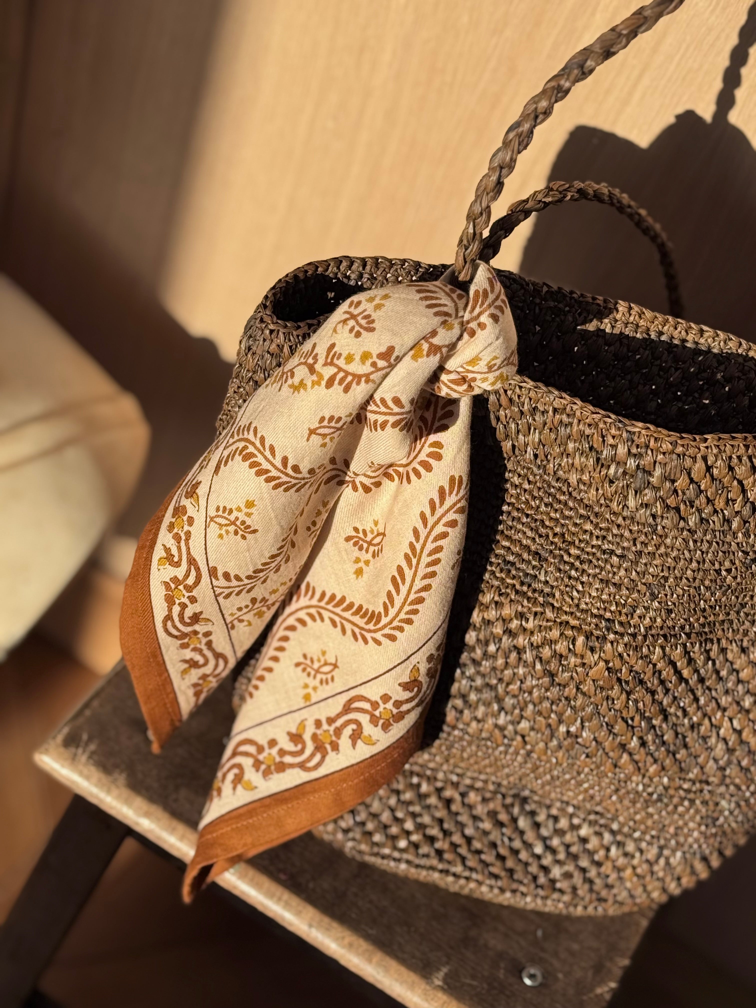 Petit foulard Antoinette Beige à bordure caramel noué à l'anse d'un panier