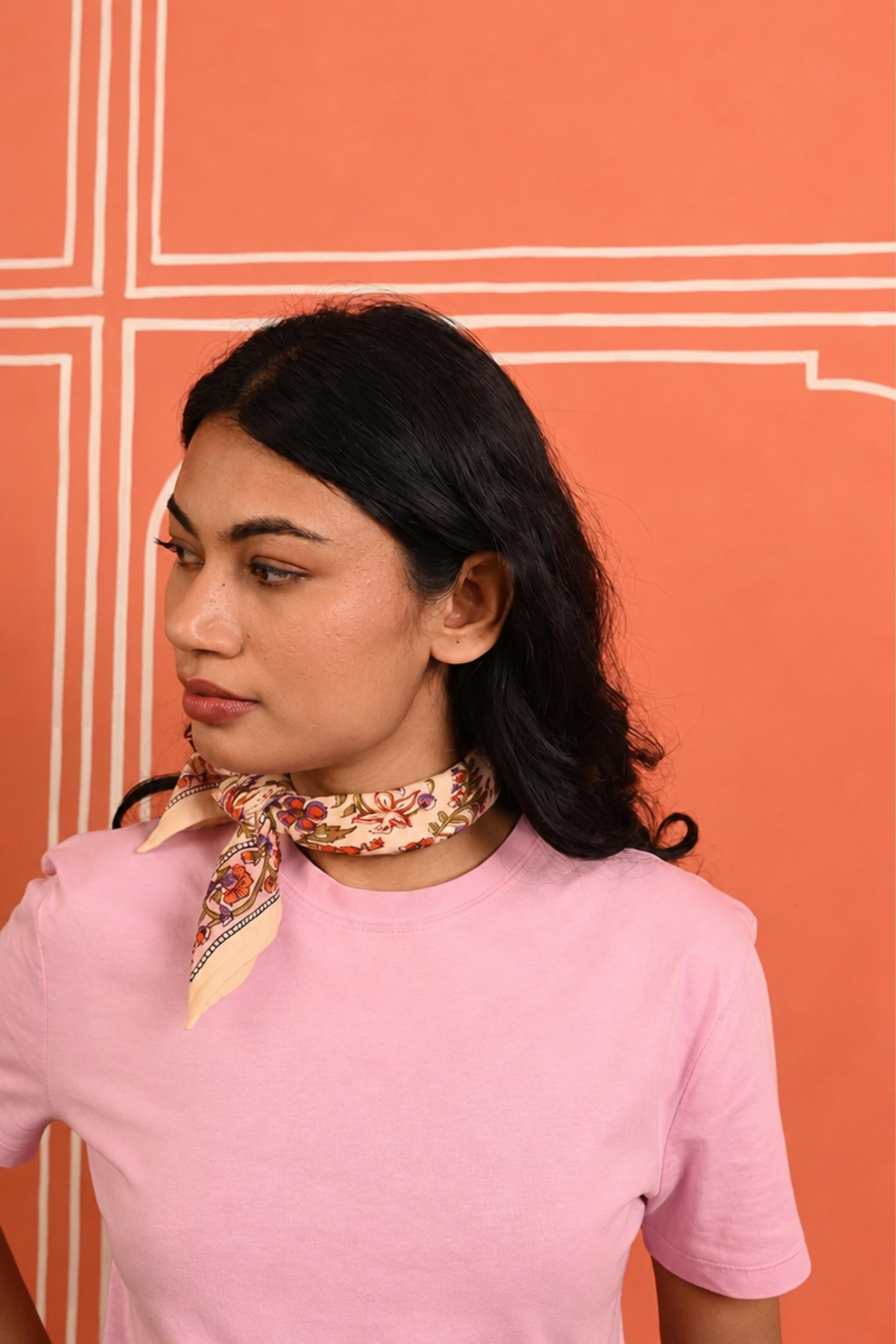 Petit foulard Calypso Flame noué au cou, porté avec un tee-shirt rose