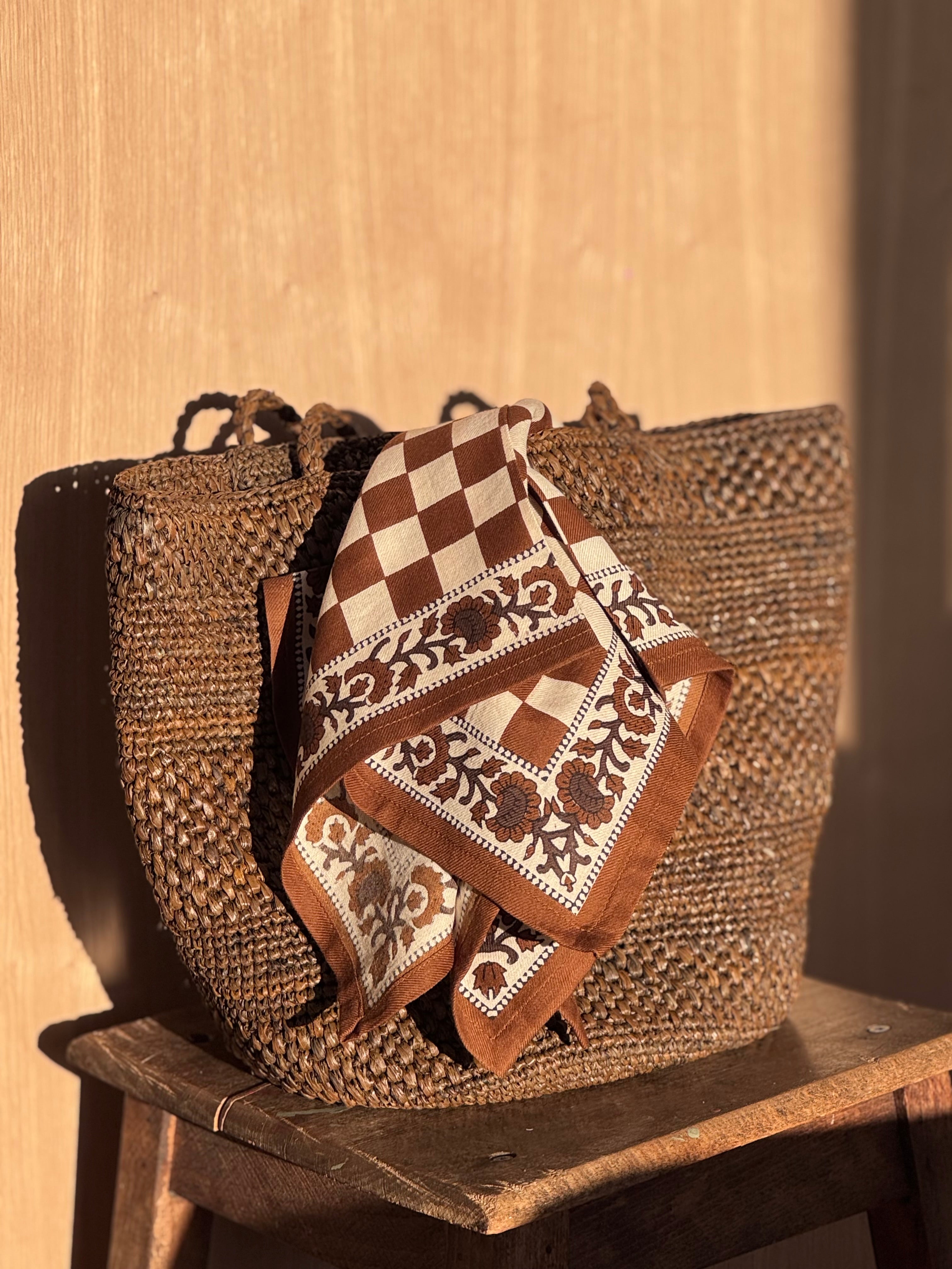 Petit foulard Checks Bistre noué sur un panier tressé posé sur un tabouret