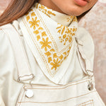 petit foulard écru type bandana porté par une jeune femme vêtue de blanc cassé