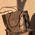 Petit foulard Mercure Bistre noué à l'anse d'un panier tressé