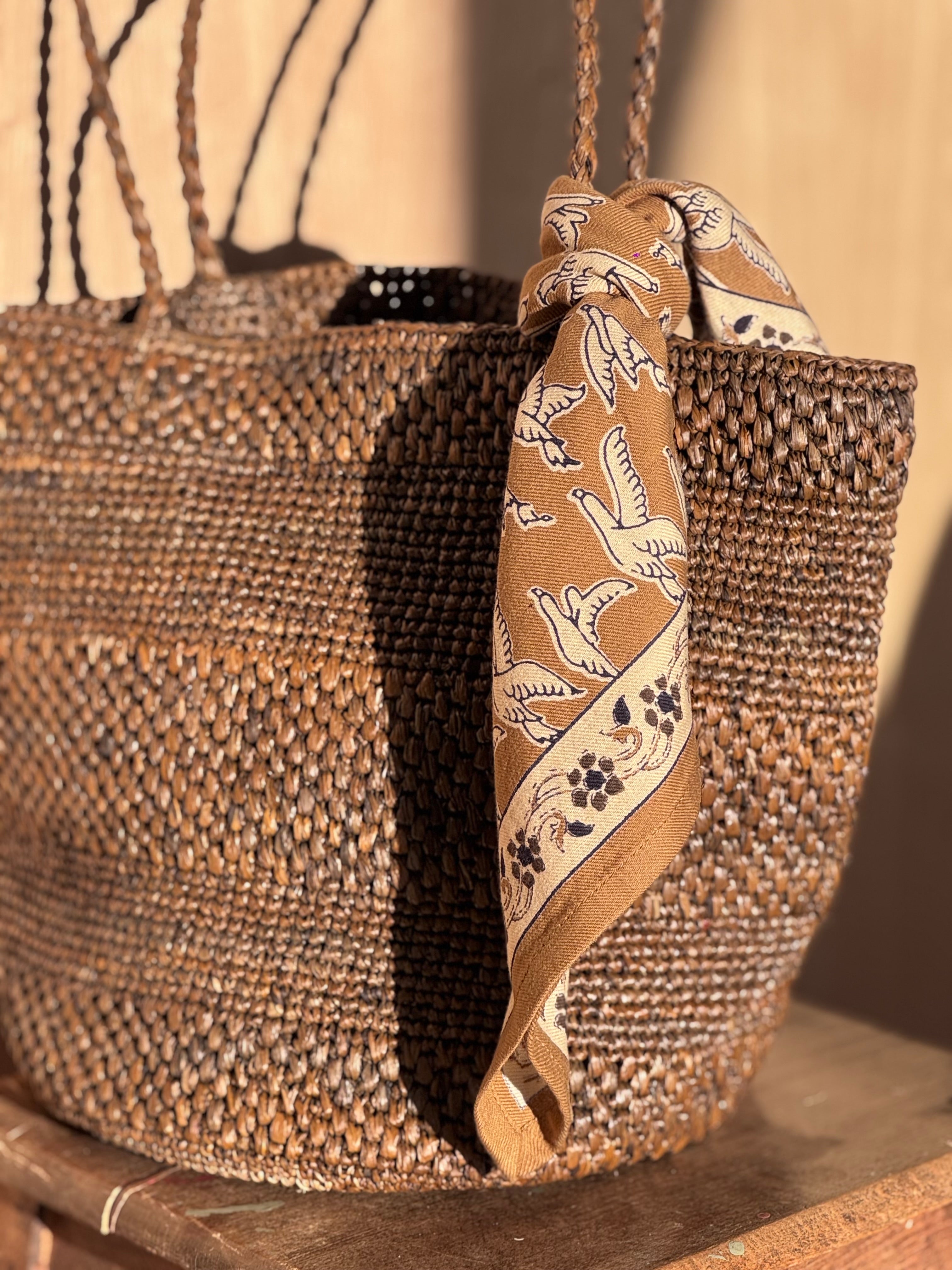 Gros plan sur le petit foulard Mercure Bistre noué sur un panier en osier