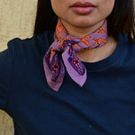 Petit foulard violet et orange vif roulé et noué autour du cou d’une jeune femme indienne
