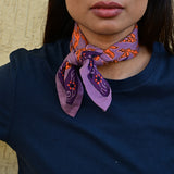 Petit foulard violet et orange vif roulé et noué autour du cou d’une jeune femme indienne