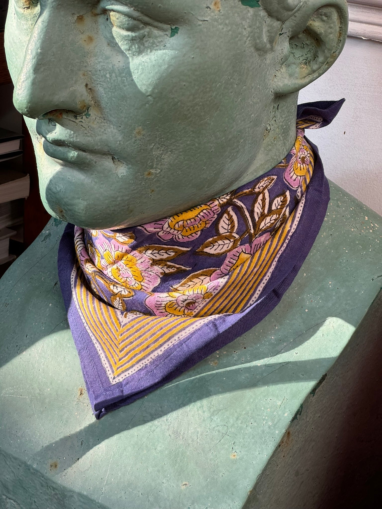 Petit foulard N°113 Bleu de byzantine, fleurs violettes et bordure moutarde, noué au cou d'un buste