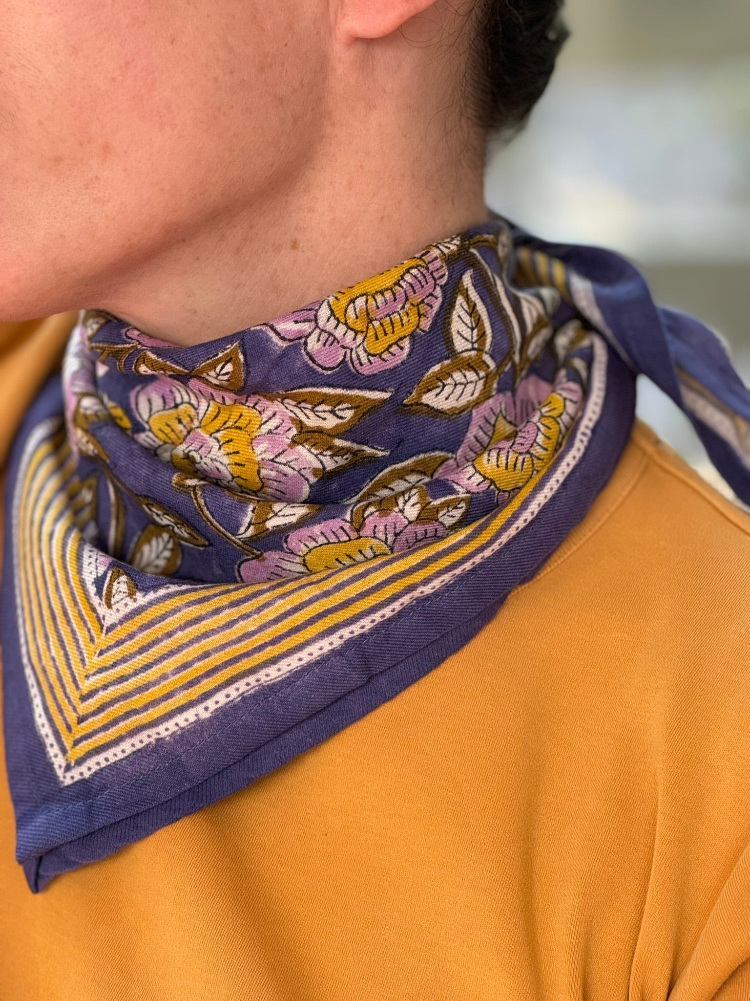 Gros plan sur le petit foulard N°113 Bleu de byzantine noué au cou, tee-shirt moutarde