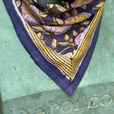 Gros plan sur le petit foulard N°113 Bleu porté par un buste, bordure moutarde