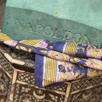 Petit foulard N°113 Bleu posé sur un buste et une table marquetée