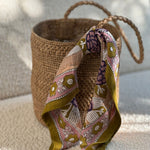 petit foulard penelope myrtille de byzantine, imprimé fleuri vert, attaché à un sac main