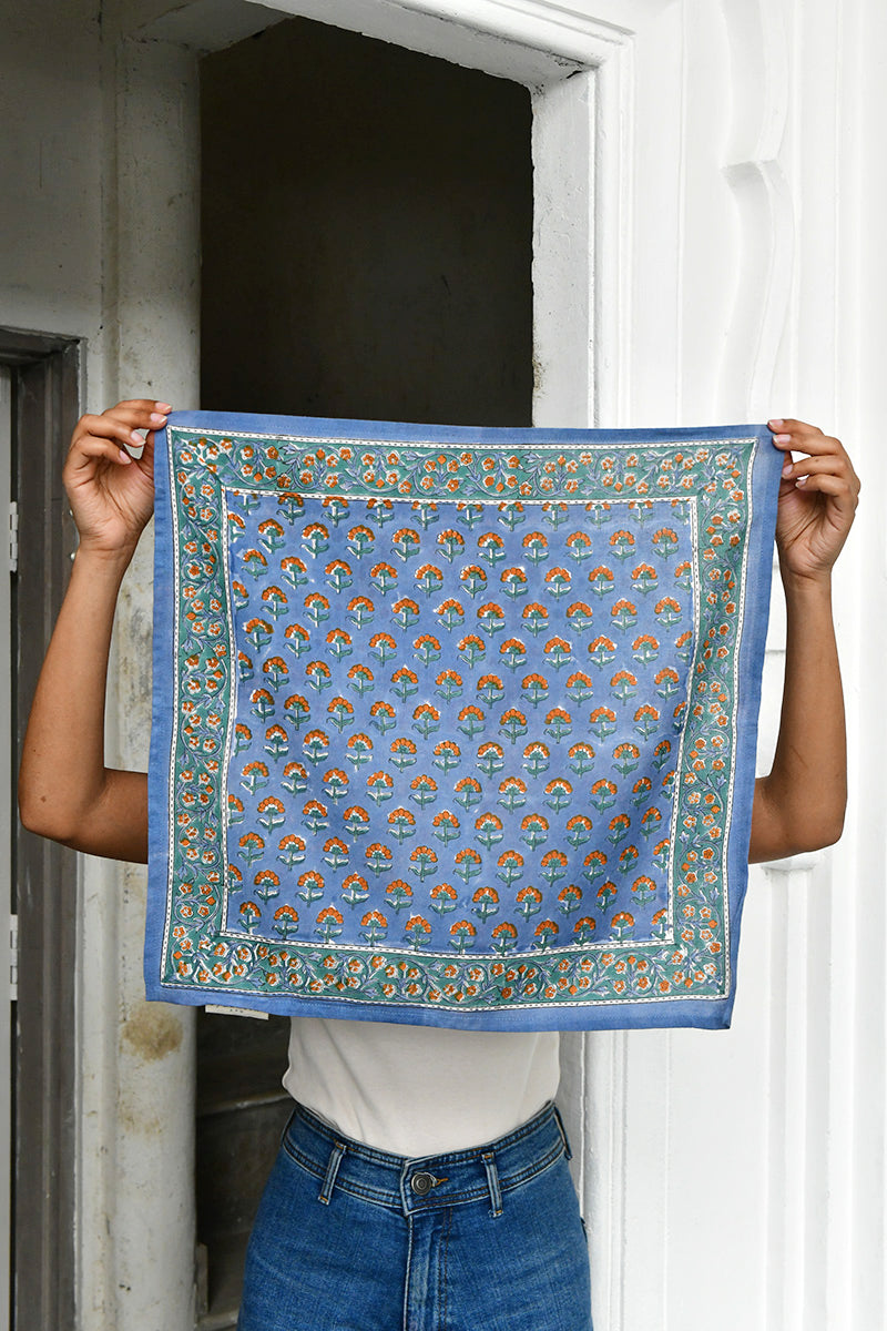 Petit foulard Séléné Bleu horizon déplié, tenu devant une porte