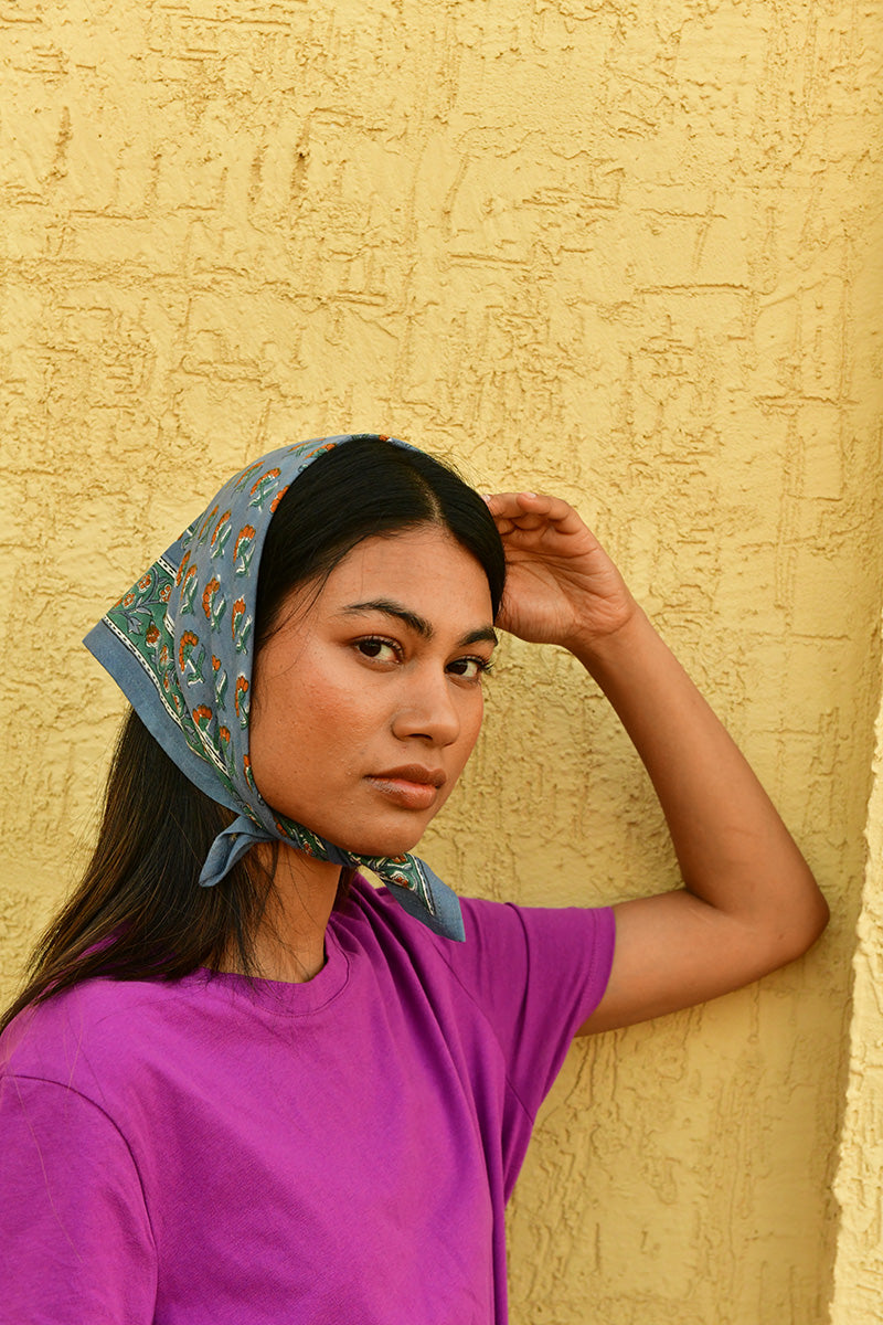 Petit foulard Séléné Bleu horizon porté en fichu, main posée sur la tête