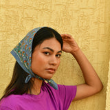 Petit foulard Séléné Bleu horizon porté en fichu, main posée sur la tête