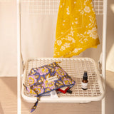 Petite trousse beauté N°113 Bleu couchée sur une chaise blanche, avec un sérum