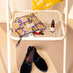 Petite trousse beauté N°113 Bleu de Byzantine sur une chaise, mocassins au sol
