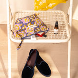 Petite trousse beauté N°113 Bleu de Byzantine sur une chaise, mocassins au sol