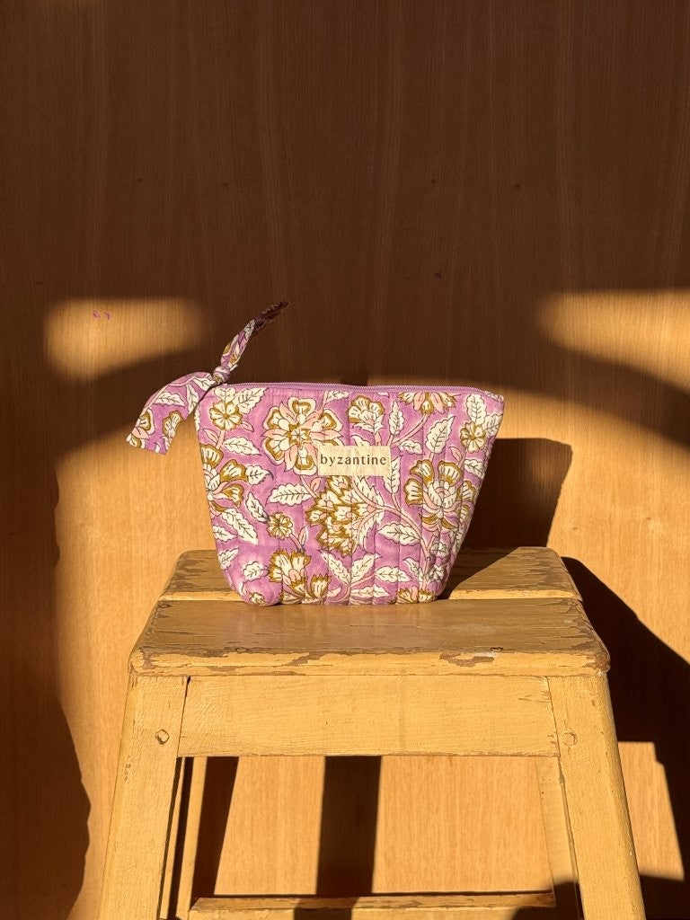 Petite trousse beauté Carthage Lilas à nœud posée sur un tabouret en bois