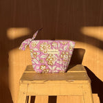 Petite trousse beauté Carthage Lilas à nœud posée sur un tabouret en bois