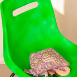 Petite trousse beauté Carthage Lilas couchée sur une chaise verte, avec du maquillage