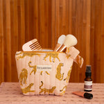 Petite trousse beauté Fauve Rose remplie de pinceaux, posée sur une caisse rose