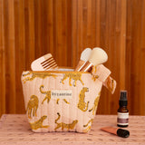 Petite trousse beauté Fauve Rose remplie de pinceaux, posée sur une caisse rose