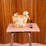 Petite trousse beauté Fauve Rose avec pinceaux et sérum, sur un tabouret