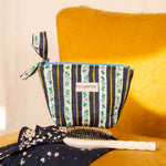 Petite trousse beauté Flora Bleu marine à nœud, avec une brosse, sur un fauteuil