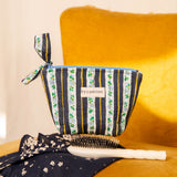 Petite trousse beauté Flora Bleu marine à nœud, avec une brosse, sur un fauteuil