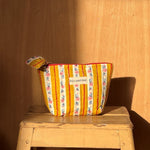 Petite trousse beauté Flora Passion de byzantine posée sur un tabouret en bois
