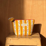 Petite trousse beauté Flora Passion de byzantine posée sur un tabouret en bois