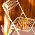 Petite trousse beauté Flora Passion sur une chaise blanche, foulard fleuri sur le dossier